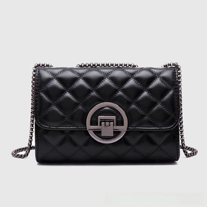 Detail of black quilted leather crossbody bag with metal chain strap and twist lock