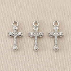 Close-up of three silver Baroque cross pendants with inlaid sparkling zircon stones