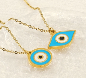 Macro detail of golden Evil Eye pendants with blue enamel on a textured glass tray