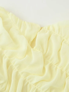 Close-up of pleated chiffon fabric texture and delicate stitching on yellow dress