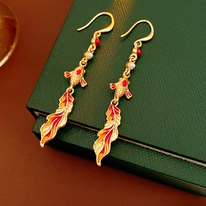 Detail of vintage koi enamel earrings with golden tassels and pearls on a velvet box