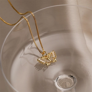 Artistic close-up of a gold butterfly pendant necklace with sparkling zircons in a glass