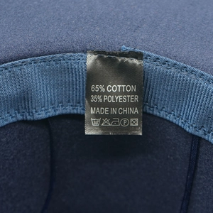 Dettaglio dell'etichetta interna di un cappello fedora in feltro blu con 65% cotone
