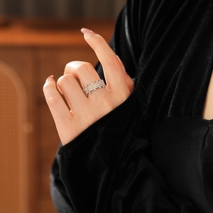 Close-up of a silver and gold pavé zircon ring worn by a model in warm lighting