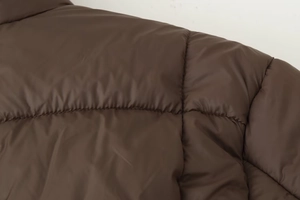 Gros plan sur la veste matelassée marron montrant les coutures et la matière