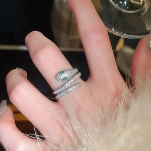 Detailed view of silver snake ring with green stone eyes and white cubic zirconia