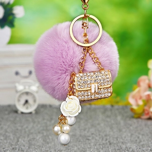 Detailed view of purple faux fur pompom keychain with crystal bag charm and pearl tassels