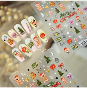 Detail of Christmas nail art stickers featuring cute bears and trees on soft pink nails