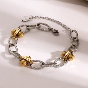 Detail of two-tone stainless steel chain bracelet with gold beads and textured links