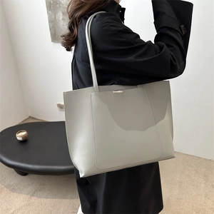 Fashionable light grey large capacity tote bag worn by model in a minimalist setting