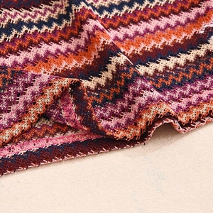 Detail shot of multicolor wave pattern knit fabric featuring orange and purple zigzags