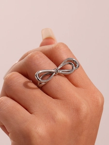 Polished silver irregular bow ring shown on model hand with minimalist design