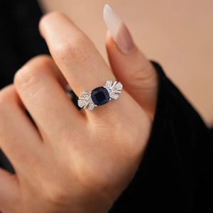 Détail d'une bague en argent avec pierre bleue taille coussin portée au doigt