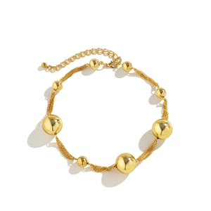 Detail of gold choker necklace with large high-gloss metallic beads and multi-strand chains