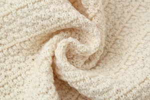 Vue macro détaillée de la texture du tricot gaufré blanc crème et de la matière douce