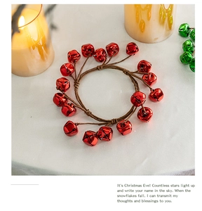 Detail of red Christmas bell wreath with woven rope on white silk and warm candle