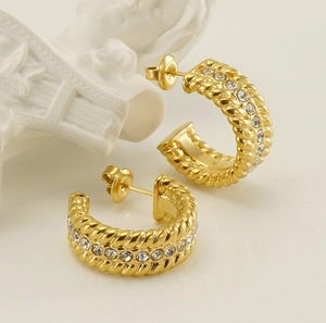Detail of gold C-shaped twisted rope earrings with white rhinestones on artful display