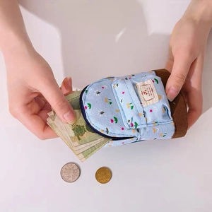 Sky blue floral canvas mini backpack coin purse being held to show storage capacity