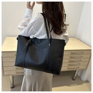 Detail of a black large capacity tote bag with adjustable strap and external pocket