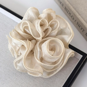 Close-up of elegant ivory tulle flower scrunchie with layered pleated fabric textures