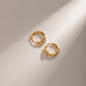 Detail of 18k gold plated stainless steel hoop earrings with teardrop zircon in soft light