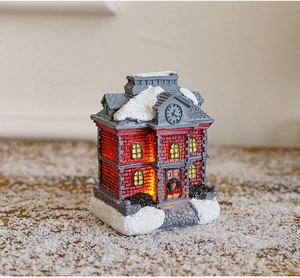 Detail of a glowing Christmas resin house with warm LED lights on a snowy background