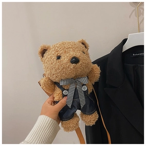 Detailed view of brown plush bear crossbody bag with plaid bow and denim overalls strap