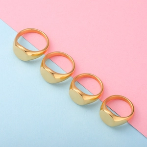 Detailed view of four polished gold oval signet rings arranged on a dual-tone background