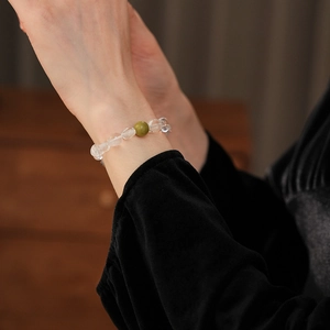Détail d'un bracelet en cristal blanc et bois de santal vert porté au poignet d'une femme