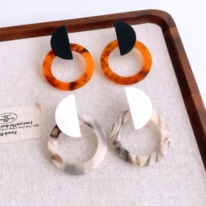 Minimalist resin geometric hoop earrings with marble and amber texture on linen tray