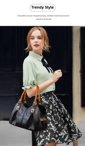 Chic black pebble grain tote bag with brown leather handles held by lifestyle model
