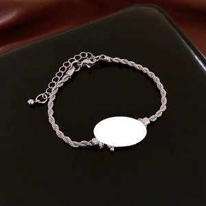 Detail of silver twisted rope bracelet with oval pendant on black leather texture