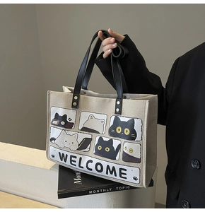 Detail of canvas tote bag showing cat comic print and sturdy leather handles