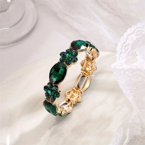 Detailed macro view of luxury stretch bracelet with green oval gemstones in gold setting