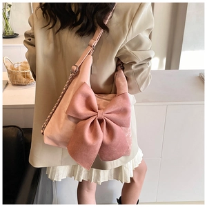 Macro shot of the large pink bow detail and soft suede texture on this stylish shoulder bag