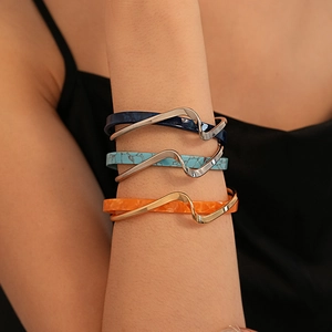 Detail of three stacked gold plated bangles with colorful resin inlays on a model arm