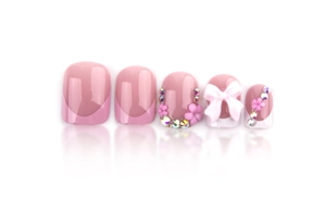 Detail of pink French press-on nails featuring rhinestones, floral art and a 3D bow