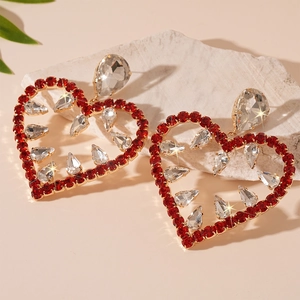 Detailed view of red heart drop earrings with white crystals on a natural stone base