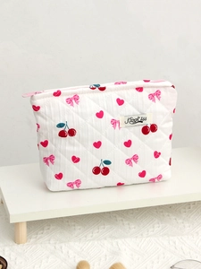 Detailed view of white quilted makeup bag featuring cherry, heart, and bow patterns
