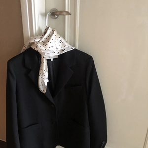 Premium men's silk scarf with white polka dot pattern styled on a black blazer jacket