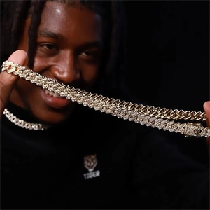 Detail of a bold gold Cuban link necklace with sparkling crystals shown on a male model