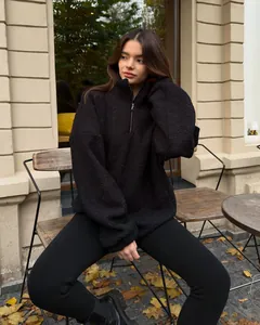 Detail of black fleece teddy hoodie featuring silver half-zip and oversized drop shoulder