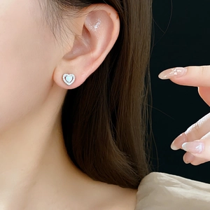 Close-up of heart-shaped opal earrings with silver diamond setting on a female model