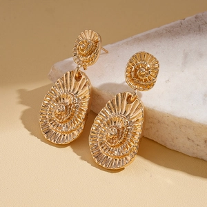 Gros plan de boucles d'oreilles dorées avec texture en spirale et design de goutte gaufré