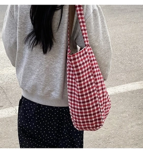 Outdoor shot showing the red and white houndstooth wool tote bag worn on a shoulder