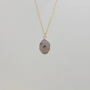 Detailed view of a gold-plated necklace featuring a planet and star engraved pendant