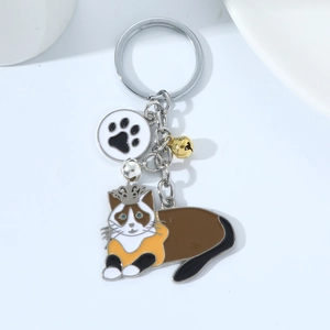 Macro detail of enamel cat keychain with crown, paw print charm and twin metal bells