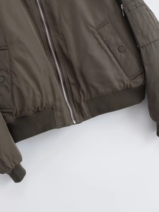 Detail of olive green bomber jacket featuring ribbed hem and metal zipper closure