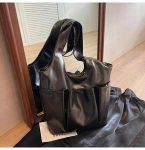 Mirror reflection showing the back detail of a black multi-pocket large shoulder tote bag