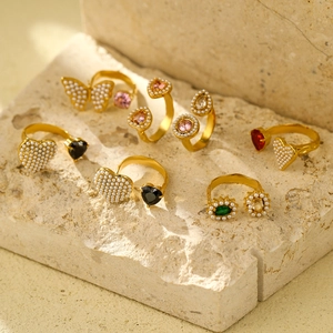 Double-layered gold titanium steel rings set with crystals and pearls on beige stone